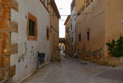 Rear view of man walking on street amidst buildings