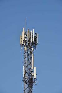 Low angle view of communications tower against clear blue sky