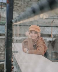 Portrait of young woman sitting on railing