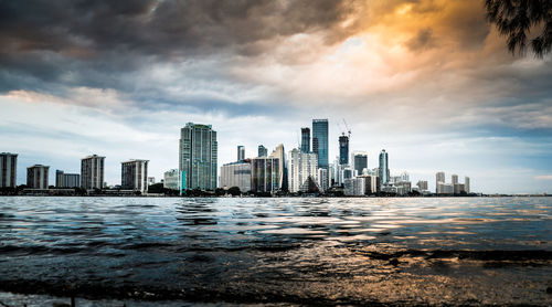 View of city by sea against cloudy sky