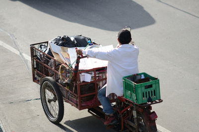 Rear view of vendor riding motor cart on road