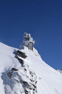 Low angle view of snowcapped mountain against blue sky