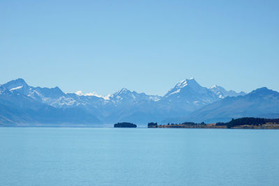 Scenic view of sea and snowcapped mountains against clear blue sky