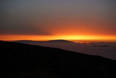 Silhouette landscape against dramatic sky during sunset