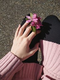 Low section of woman with purple flowers against wall