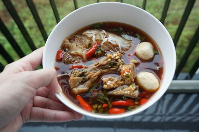 High angle view of hand holding soup in bowl