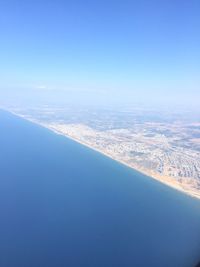 Aerial view of sea and cityscape against clear blue sky