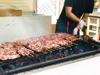 Midsection of man preparing food on barbecue grill