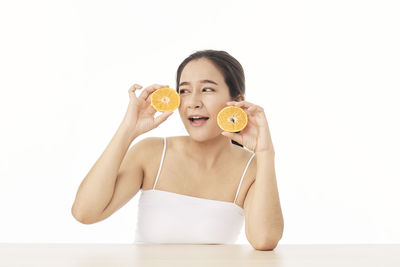 Portrait of woman holding ice cream against white background