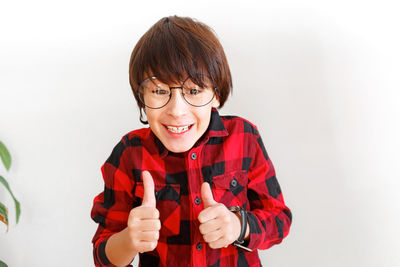 Portrait of smiling young man holding eyeglasses against white background