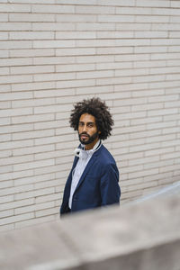 Male entrepreneur staring while standing by brick wall