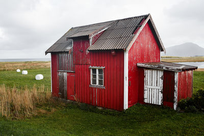 Barn on field by building against sky