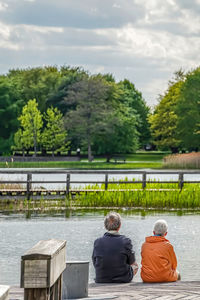 Rear view of man sitting on railing
