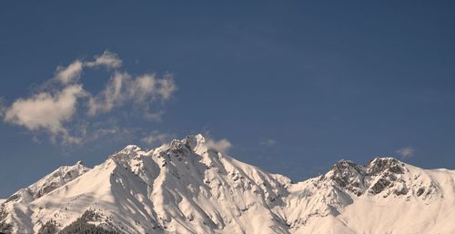 Low angle view of snowcapped mountains against sky