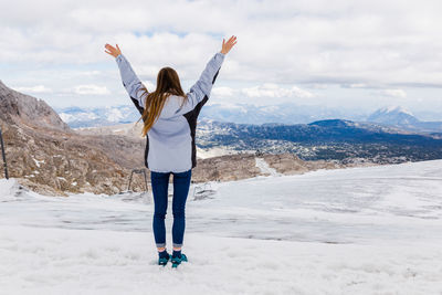 Young millennial girl enjoys the views of the alps standing on glacier