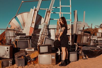 Side view of beautiful young woman standing at junkyard