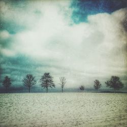 Snow covered field against cloudy sky