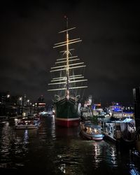 Boats moored at harbor at night