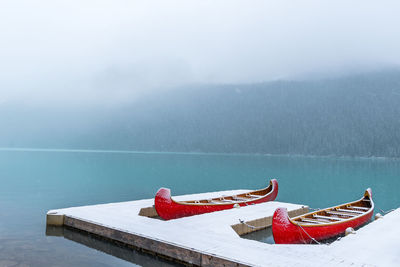 Boats moored on lake during winter