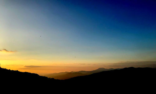 Scenic view of silhouette mountains against sky at sunset