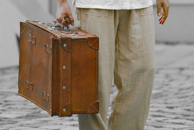 Low section of man standing with suitcase 