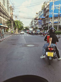 Rear view of man riding motorcycle on city street