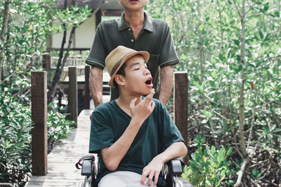 Boy sitting on wheelchair amidst plants