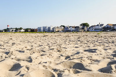 Beach by buildings against clear sky