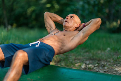 Midsection of shirtless man sitting on plant