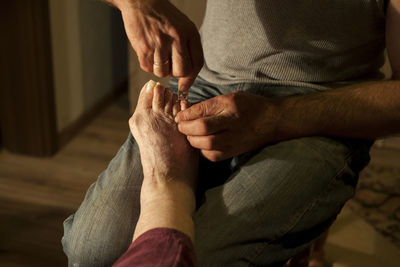 Man cutting nails of mother at home