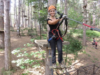 Portrait of happy woman preparing for zip lining in forest