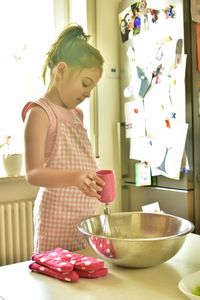 Girl holding ice cream in bowl at home