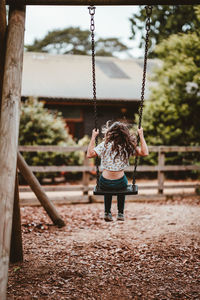 Rear view of girl on swing at playground