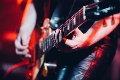 Midsection of man playing guitar at nightclub