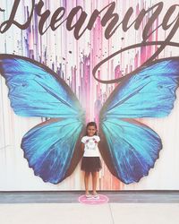 Portrait of young woman standing against wall