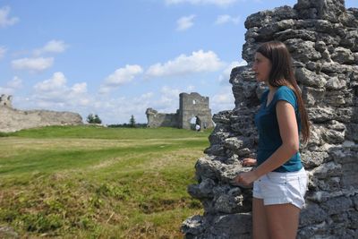 Side view of woman standing on field against ancient castle