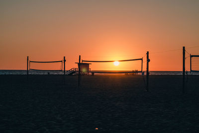 Silhouette people on beach against sky during sunset