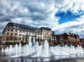 Fountain in city against sky