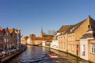 Canal passing through buildings against clear sky