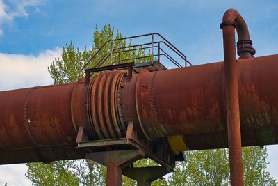 Low angle view of rusty pipes against sky