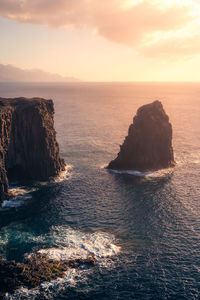 Breathtaking drone view of stone formation located in stormy sea near steep cliff against cloudy sundown sky on gran canaria island in spain