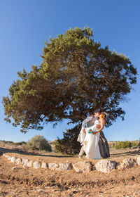 Woman standing by tree on field against clear sky