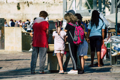 Rear view of people standing against wall in city