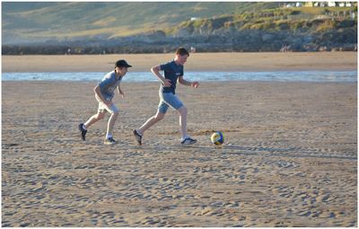 Boys playing soccer at beach