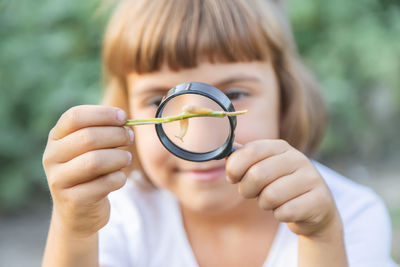 Girl looking at slug through magnifying glass