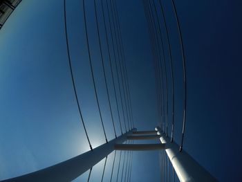 Low angle view of suspension bridge against blue sky