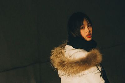 Portrait of young woman against wall