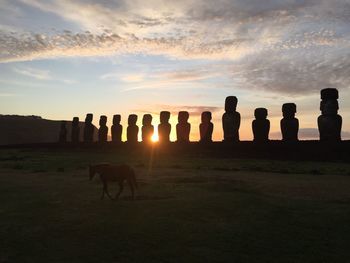 Silhouette people standing on field against sky during sunset