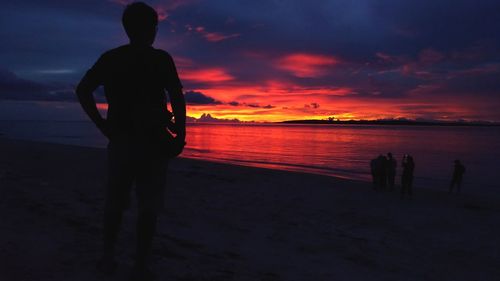 Silhouette man standing on beach against sky during sunset