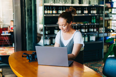 Young woman using phone while sitting on table